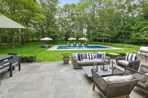 a view of a patio with couches table and chairs under an umbrella
