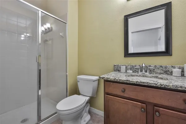 a bathroom with a granite countertop toilet a sink and mirror