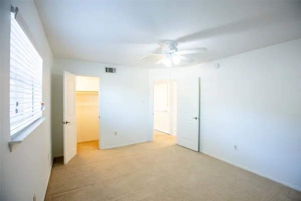 an empty room with chandelier fan and windows