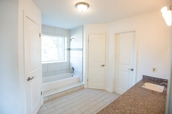 a bathroom with a tub shower and sink