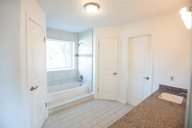 a bathroom with a tub shower and sink