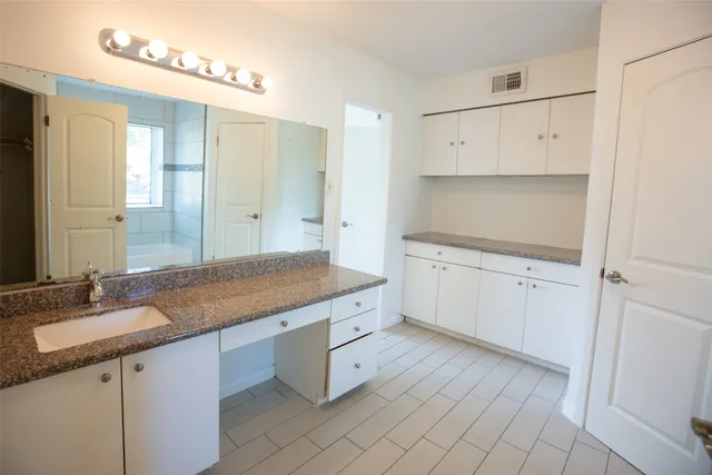 a spacious bathroom with a granite countertop sink and a mirror