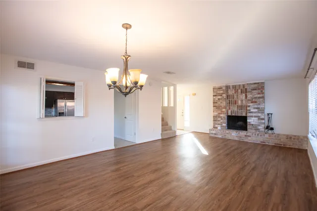 a view of a livingroom with wooden floor a fireplace and windows