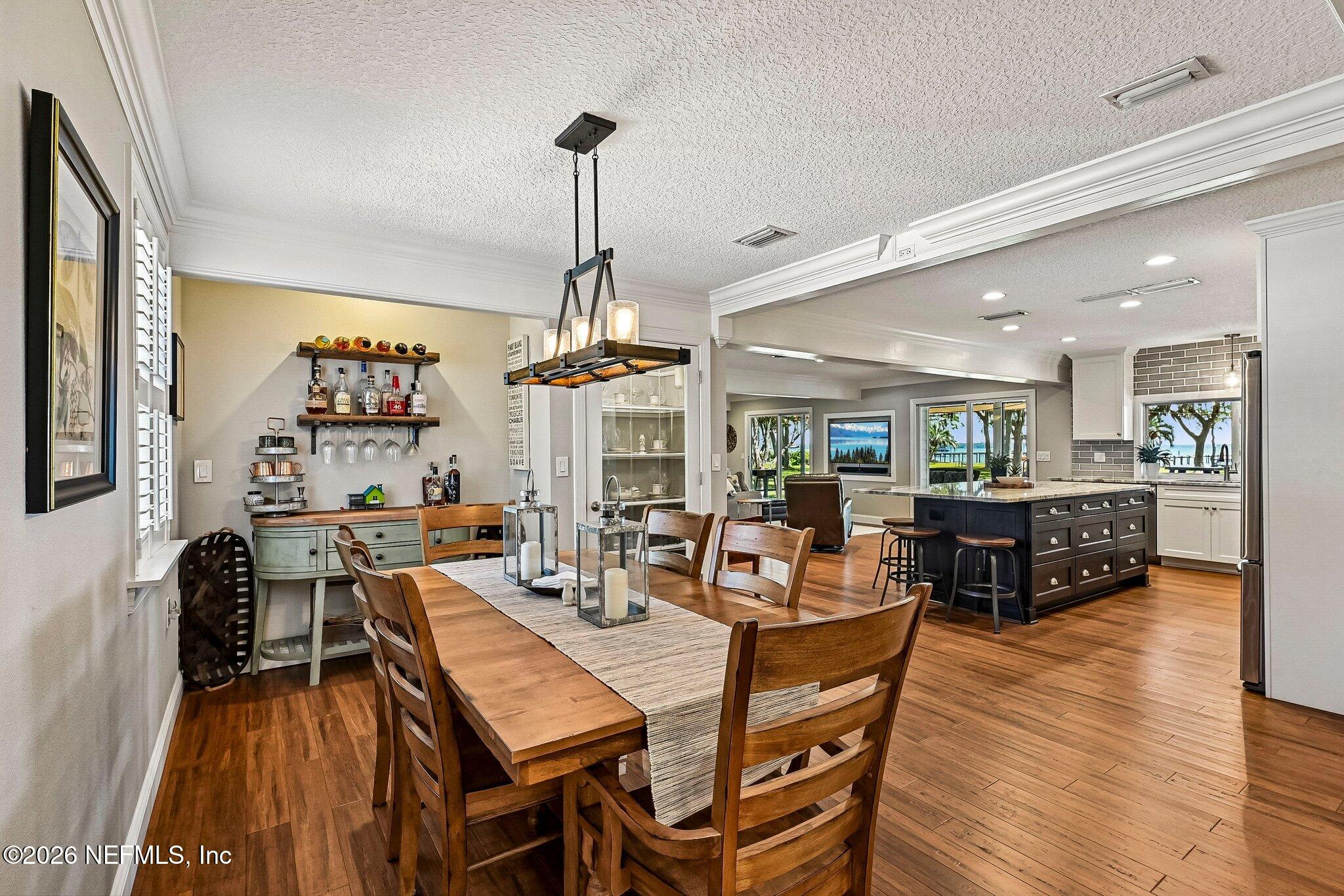4745 Raggedy Point Road Fleming Island, FL 32003 - Photo 6 of 106 a view of a dining room and livingroom with furniture wooden floor a rug a flat screen tv a painting and a chandelier