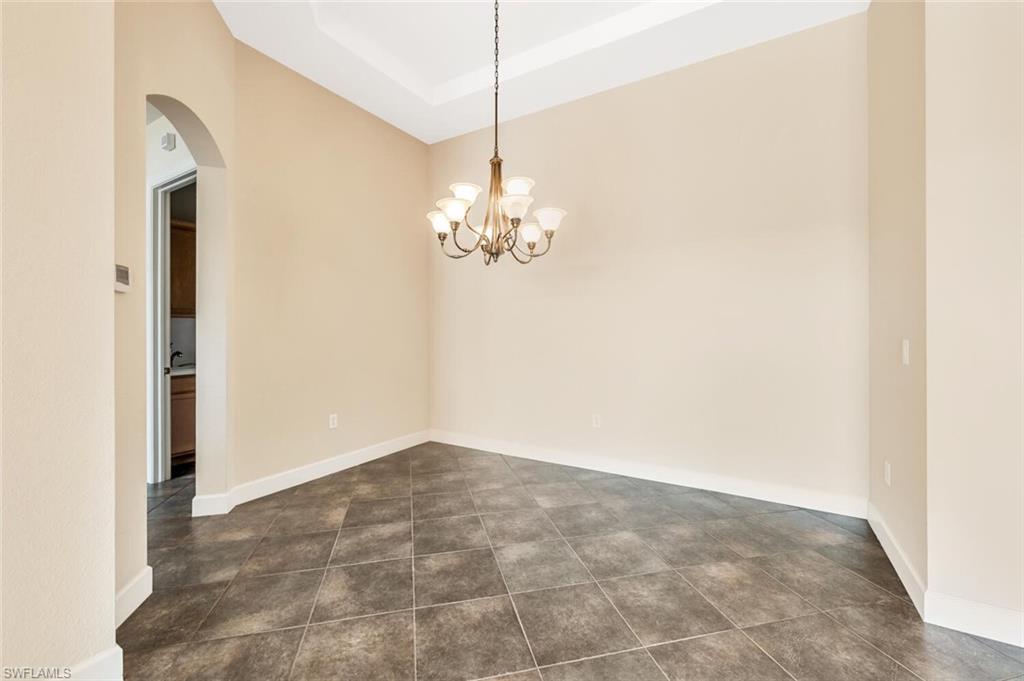8237 Valiant Drive Naples, FL 34104 - Photo 12 of 35 Tiled spare room featuring an inviting chandelier and a raised ceiling