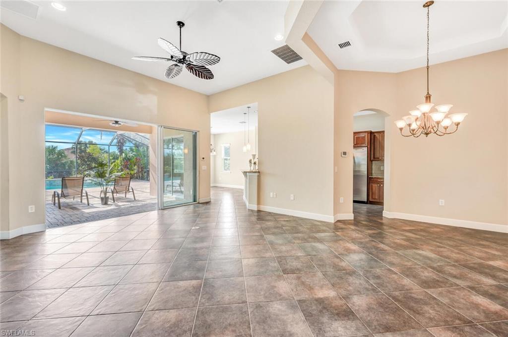 8237 Valiant Drive Naples, FL 34104 - Photo 13 of 35 Unfurnished living room featuring tile patterned flooring, ceiling fan with notable chandelier, and a towering ceiling