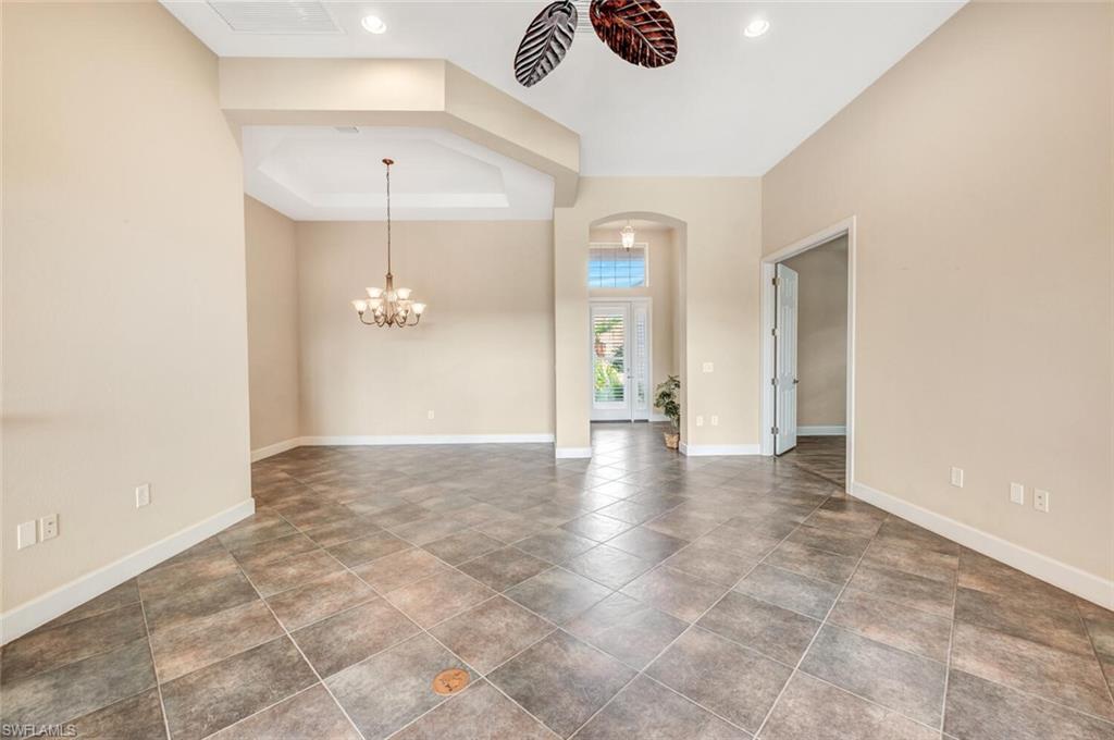 8237 Valiant Drive Naples, FL 34104 - Photo 16 of 35 Spare room with a chandelier, a tray ceiling, and dark tile patterned flooring