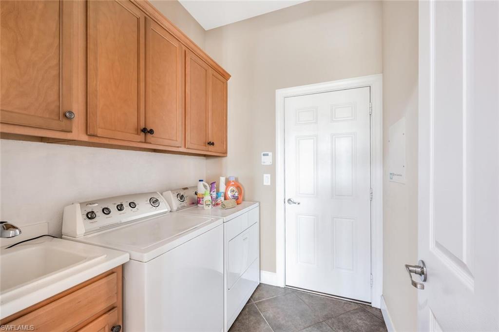 8237 Valiant Drive Naples, FL 34104 - Photo 26 of 35 Laundry room with separate washer and dryer, cabinets, tile patterned flooring, and sink