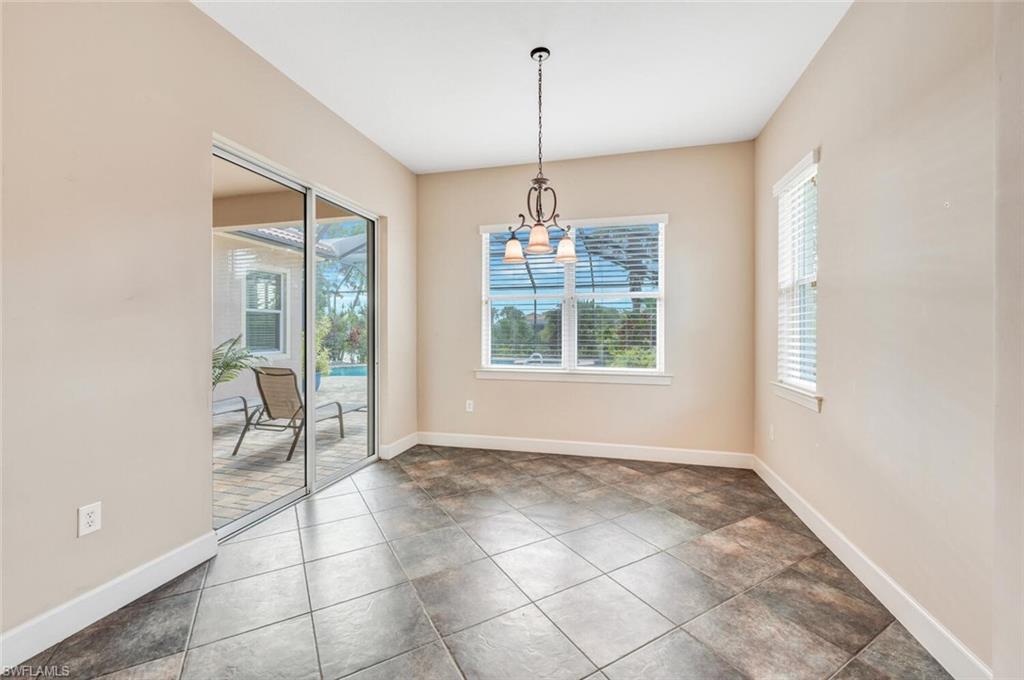 8237 Valiant Drive Naples, FL 34104 - Photo 10 of 35 Unfurnished dining area with dark tile patterned floors and an inviting chandelier