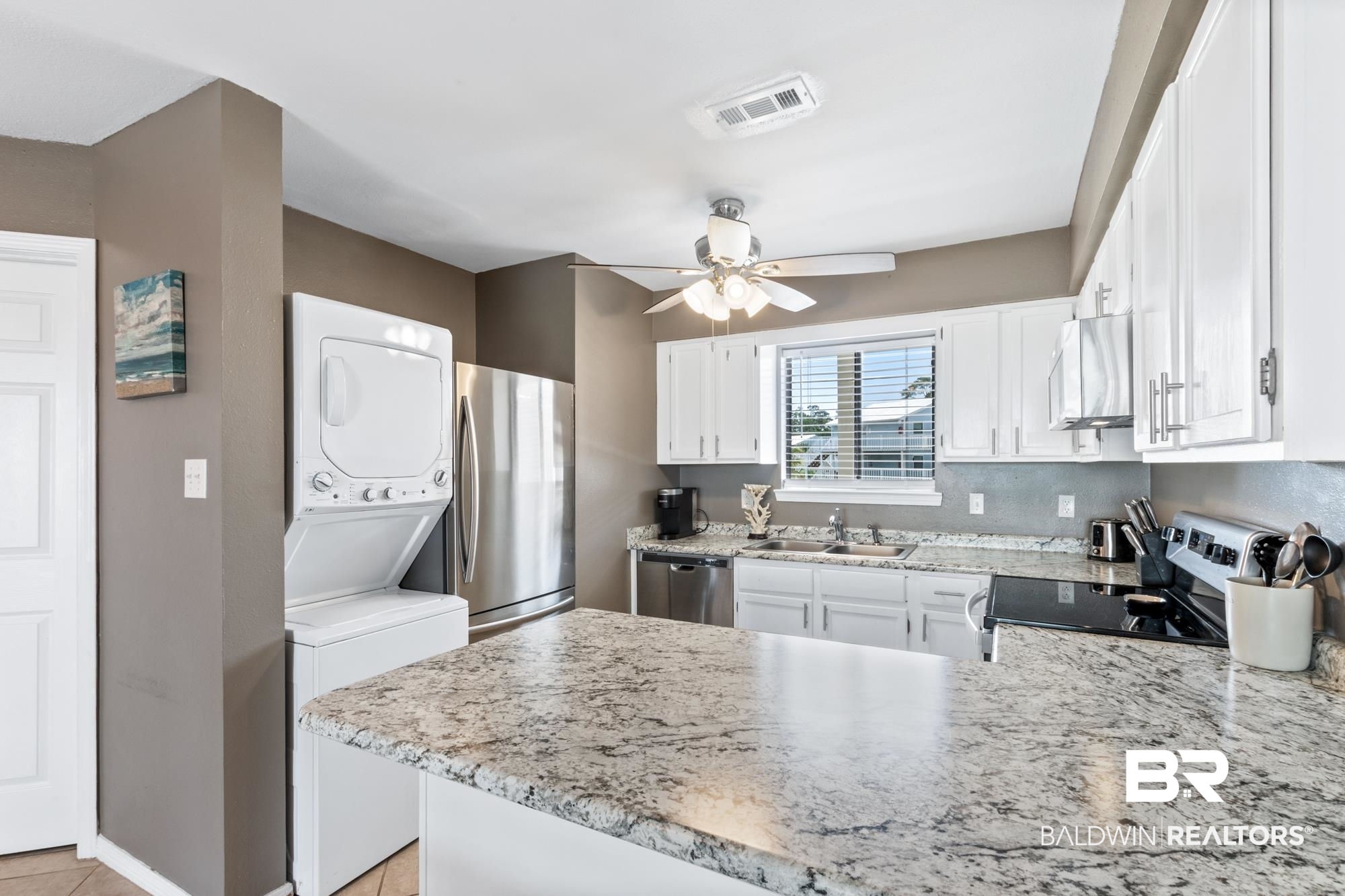 25925 -C Canal Road, Unit 203 Orange Beach, AL 36561 - Photo 5 of 57 Kitchen with appliances with stainless steel finishes, stacked washing maching and dryer, kitchen peninsula, sink, and ceiling fan