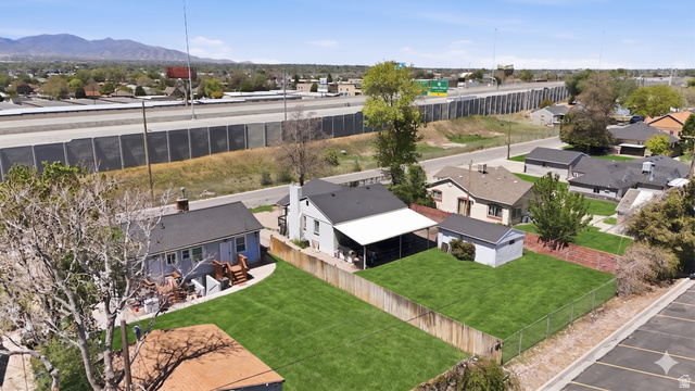 7879 Oak Street Midvale, UT 84047 - Photo 27 of 32 Expansive green lawn with a chain-link fence, mature trees, and an open carport structure