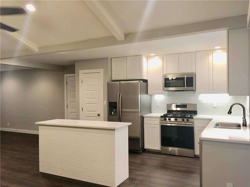 8307 Renton Drive Austin, TX 78757 - Photo 2 of 8 a kitchen with kitchen island stainless steel appliances a sink stove refrigerator and cabinets
