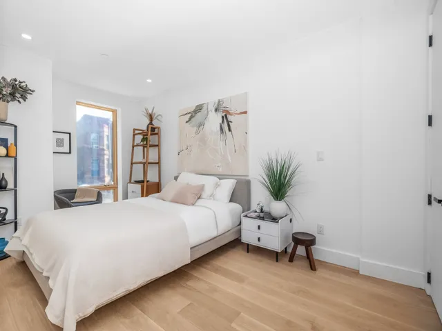 a bedroom with a bed and a potted plant on the dresser