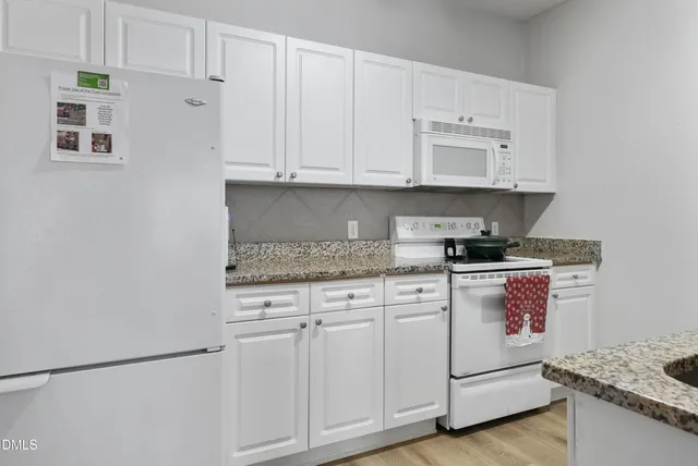 a kitchen with granite countertop white cabinets and white appliances