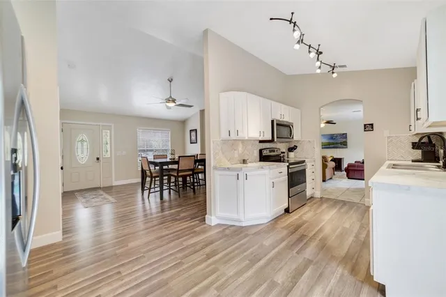 a kitchen with a refrigerator a stove top oven a dining table and chairs with wooden floor