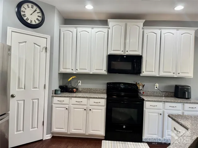a kitchen with granite countertop white cabinets and black appliances