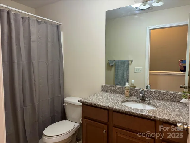a bathroom with a granite countertop sink toilet and mirror