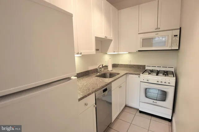 a kitchen with granite countertop white cabinets and white appliances