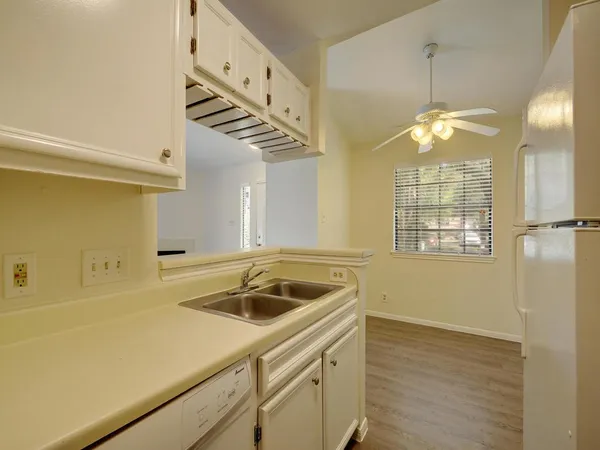 a kitchen that has a sink and a stove with wooden floor