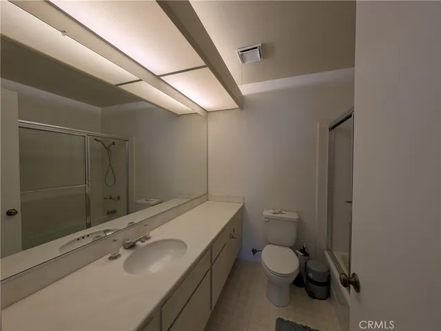 a bathroom with a granite countertop toilet sink and mirror