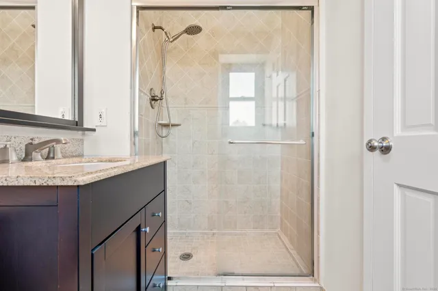 a bathroom with a granite countertop sink a mirror and a shower