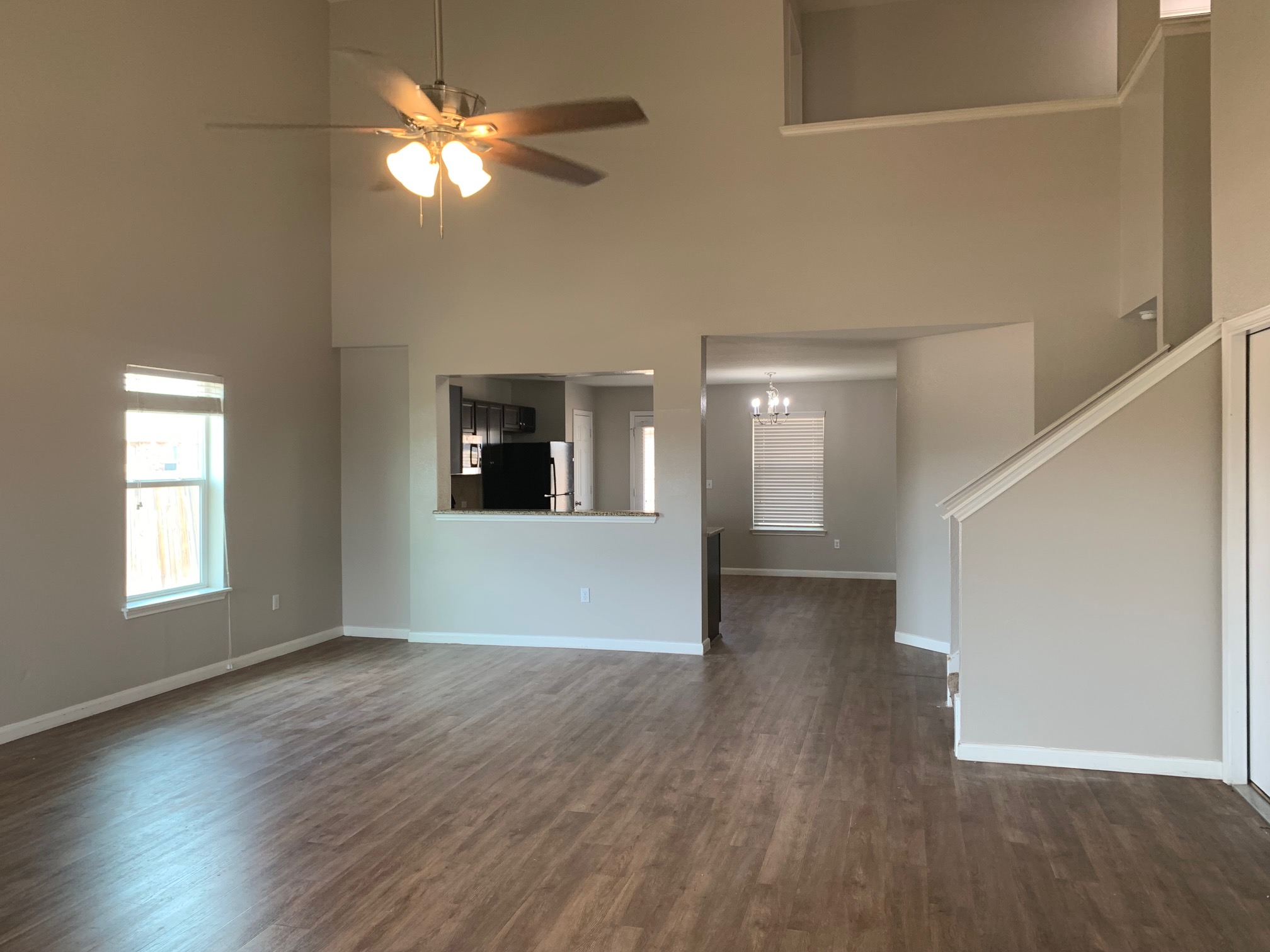 384 Discovery Kyle, TX 78640 - Photo 2 of 18 Unfurnished living room featuring dark wood-type flooring, a ceiling fan, a high ceiling, and a chandelier