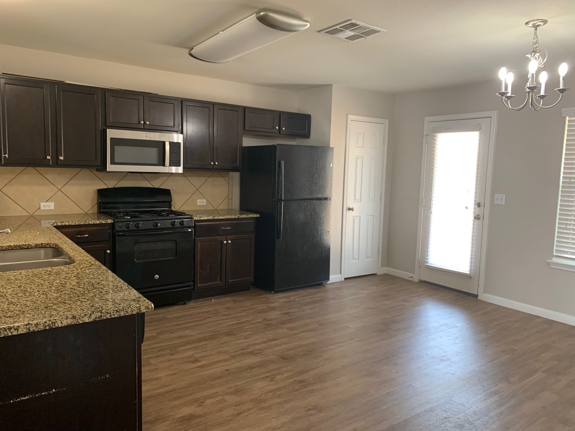 384 Discovery Kyle, TX 78640 - Photo 7 of 18 Kitchen with black appliances, light stone countertops, light wood-style flooring, and suspended lighting