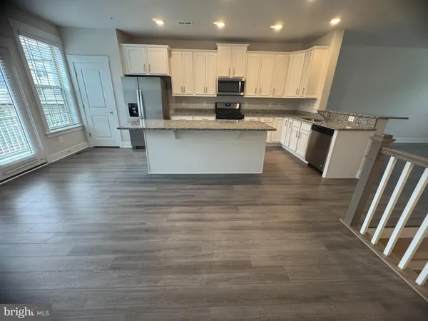 a kitchen with stainless steel appliances granite countertop a refrigerator sink and wooden cabinets