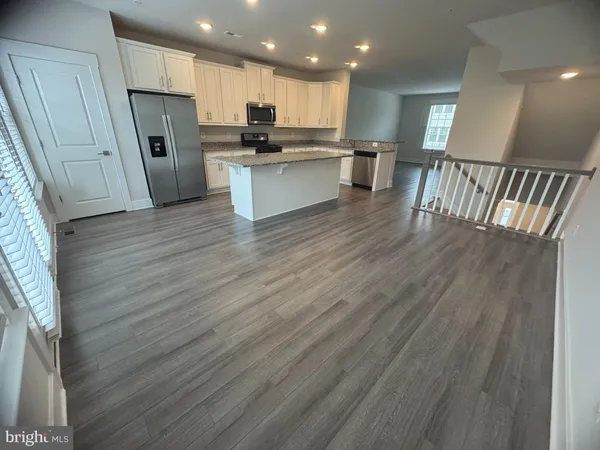 a kitchen with stainless steel appliances granite countertop a sink a stove a microwave a refrigerator a cabinets and wooden floor