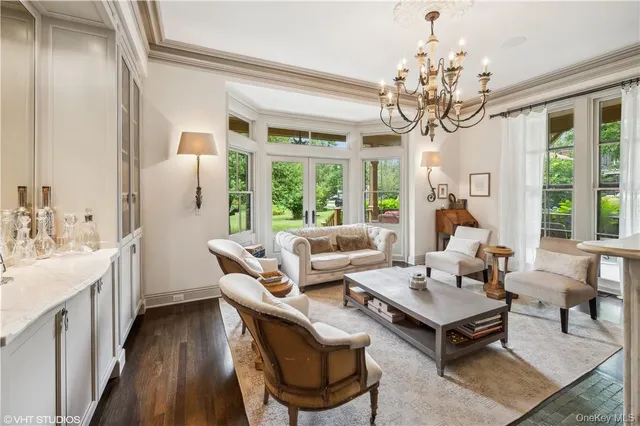 a living room with furniture a chandelier and a dining table with wooden floor