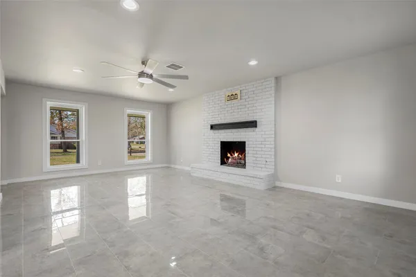 an empty room with windows and fireplace