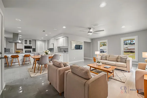 a living room with furniture kitchen view and a window