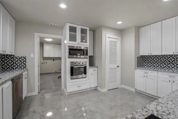 a kitchen with stainless steel appliances kitchen island granite countertop a stove a sink and a refrigerator