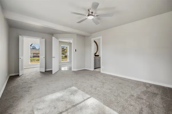 an empty room with closet and a ceiling fan