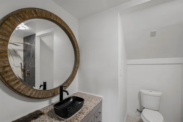 a bathroom with a toilet a sink and mirror