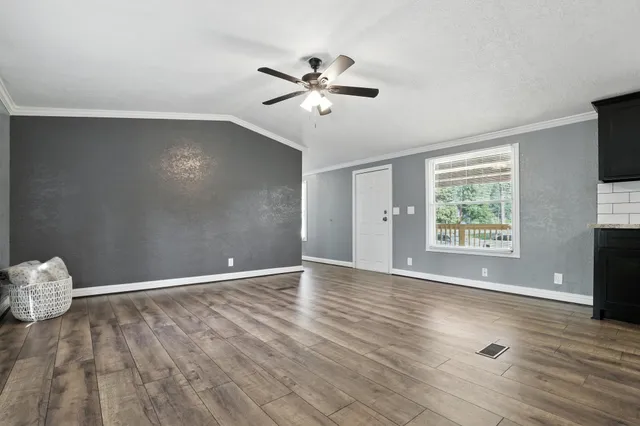 a view of an empty room with wooden floor and a window
