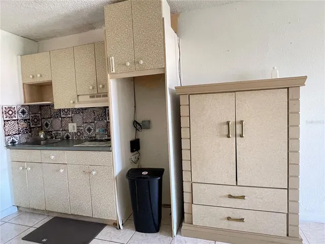 a kitchen with white cabinets and refrigerator
