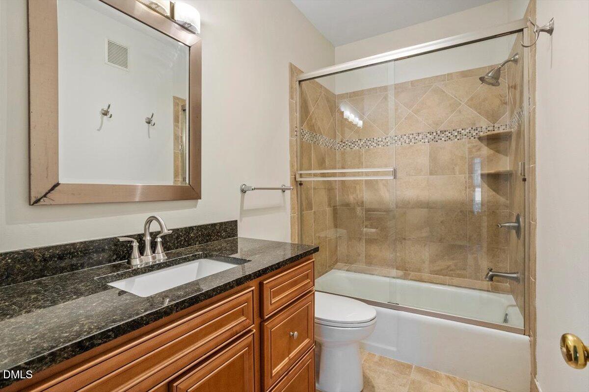 1001 Brighthurst Drive, Unit 106 Raleigh, NC 27605 - Photo 16 of 23 a bathroom with a granite countertop sink toilet and shower