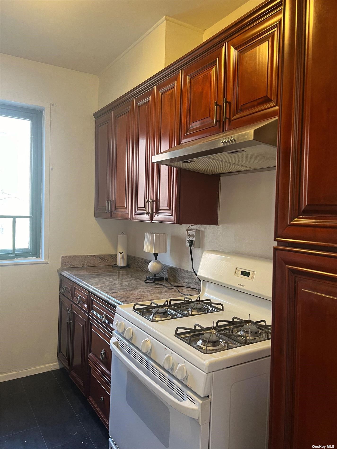 a kitchen with granite countertop stainless steel appliances stove top oven and cabinets
