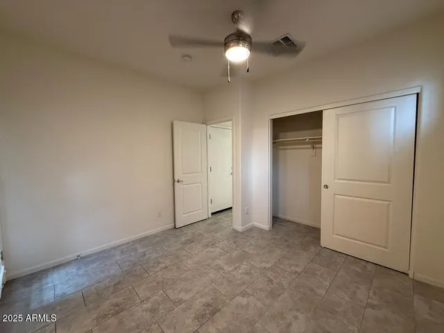 an empty room with closet and a chandelier fan