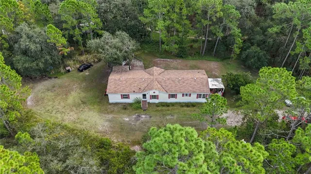 an aerial view of a house with a yard and a large tree