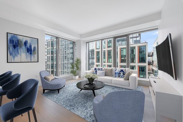 a living room with furniture a flat screen tv and large windows