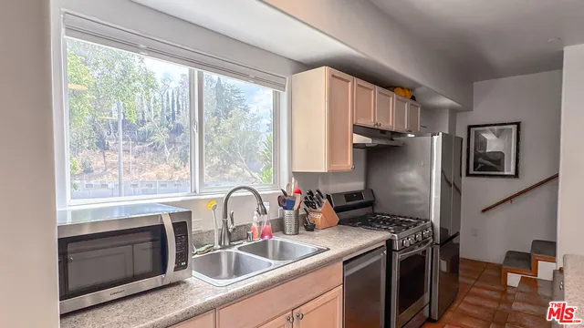 a kitchen with granite countertop a sink stainless steel appliances and furniture