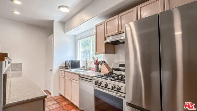 a kitchen with stainless steel appliances granite countertop a refrigerator stove and sink