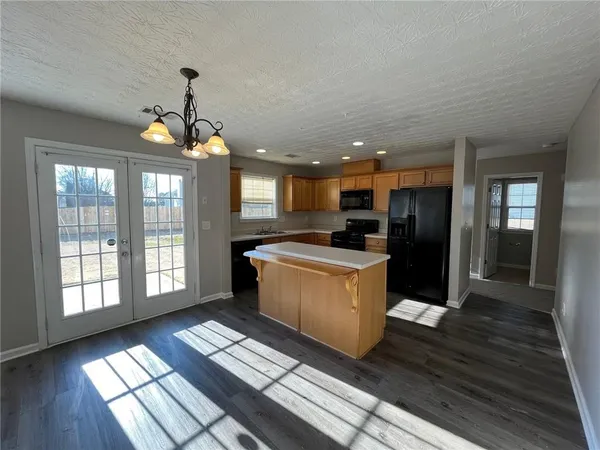 a kitchen with stainless steel appliances kitchen island granite countertop a refrigerator a sink a stove and cabinets