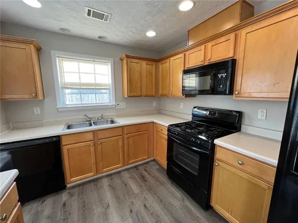 a kitchen with stainless steel appliances granite countertop wooden cabinets stove top oven and sink