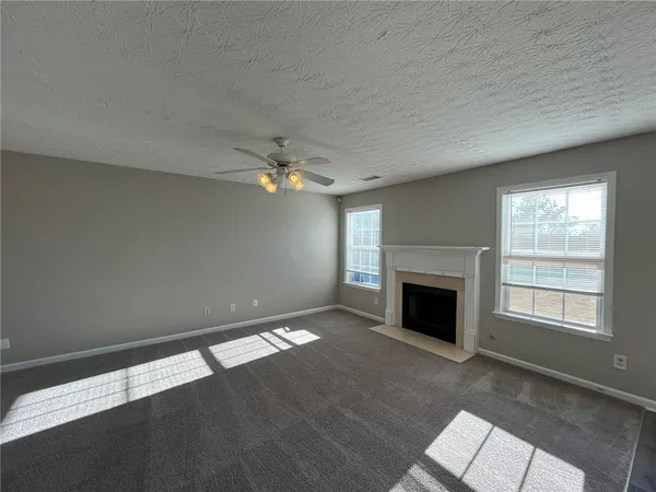 an empty room with windows fireplace and fans