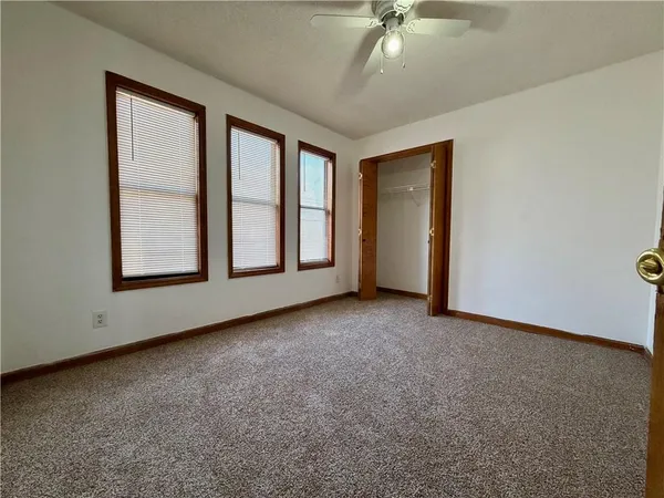 an empty room with windows and chandelier fan