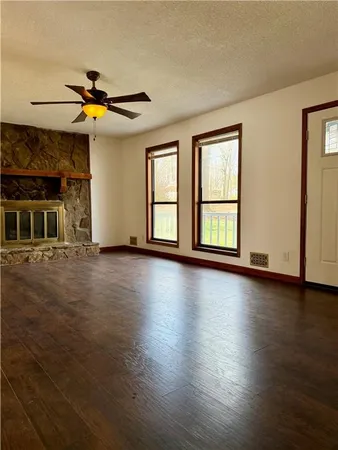 a view of an empty room with window and wooden floor