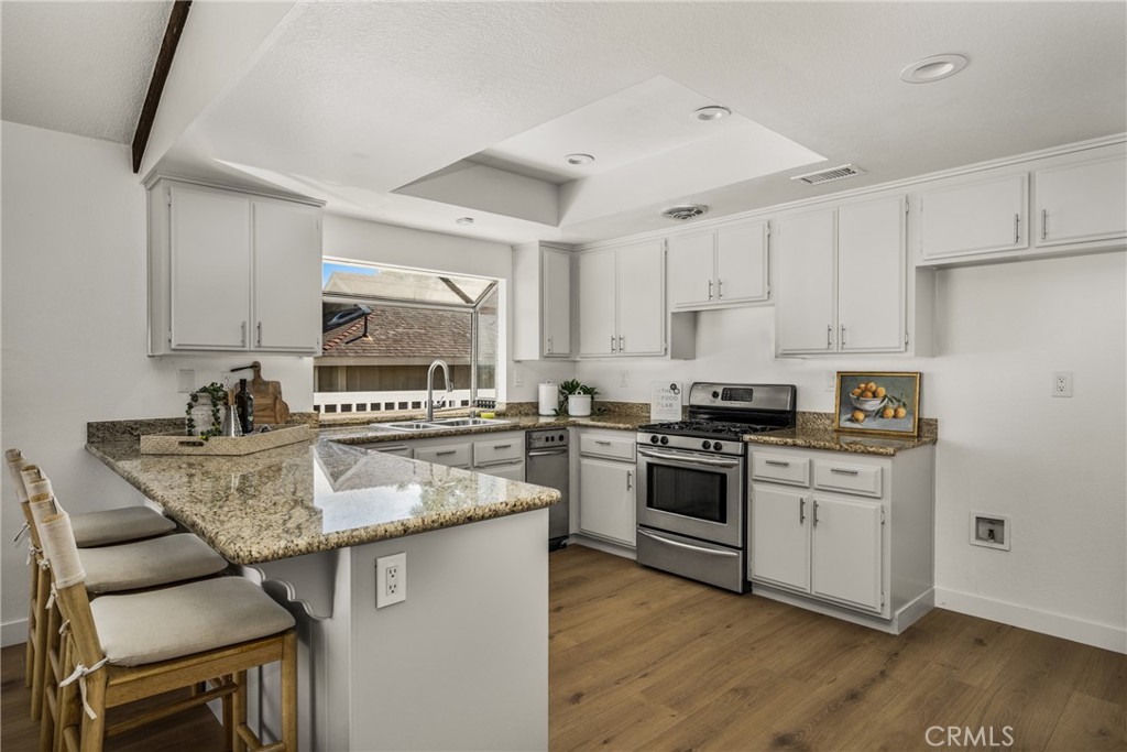 14312 Martin Riverside, CA 92503 - Photo 41 of 58 a kitchen with stainless steel appliances granite countertop a stove a sink dishwasher a microwave oven and a dining table with wooden floor